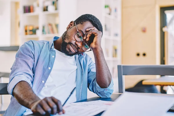 Hombre Negro Cansado Gafas Apoyadas Mano Durmiendo Mientras Trabaja Plano —  Fotos de Stock