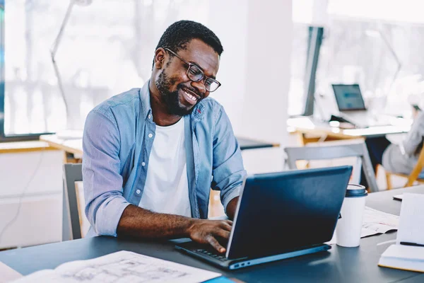 Афроамериканець Окулярах Працює Ноутбуком Радістю Посміхається Сидячи Столом Біля Великих — стокове фото
