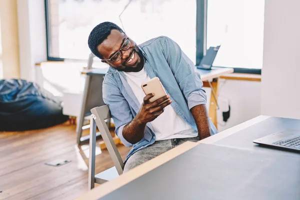 Joyful Black Man Glasses Looking Smartphone Screen Laughing While Sitting — Stock Photo, Image