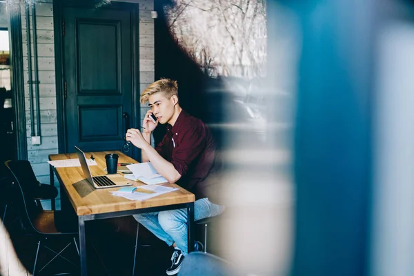 Beyaz tişörtlü ve kırmızı tişörtlü Asyalı bir erkek cep telefonuyla sohbet ediyor.