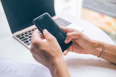 Uzaktan çalışma sırasında cep telefonu klavyesinde yazma becerisi olan bir kadının görüntüsü, milenyum çağında internet video bloğu seyreden bir kadın, açık kablosuz internete bağlanan mobil bir cihaz.