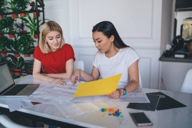 Çok ırklı, güler yüzlü kadınlar, gündelik giysiler içinde evrak işleriyle uğraşıyorlar. Gazeteler ve akıllı telefonlar ile birlikte modern ışık yaratıcı çalışma sahasında oturuyorlar. 
