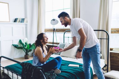 Mutlu çift gündelik giysiler içinde yıldönümünü kutluyor ve gülümsüyor. Bu arada gözlüklü adam parlak yatak odasında kız arkadaşına hediye veriyor.