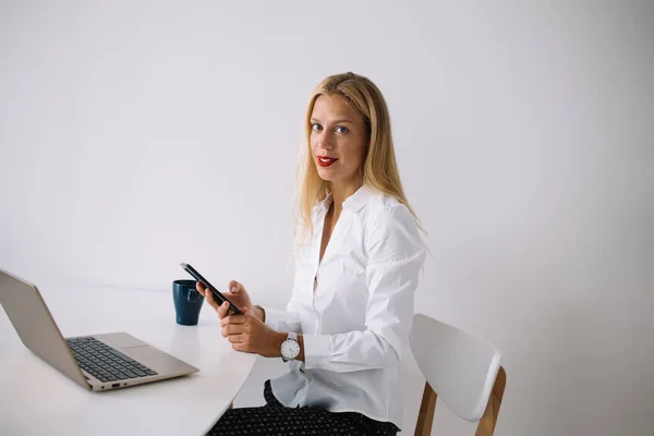 Zufriedene Junge Blonde Frau Sitzt Weißen Tisch Mit Blauer Tasse — Stockfoto