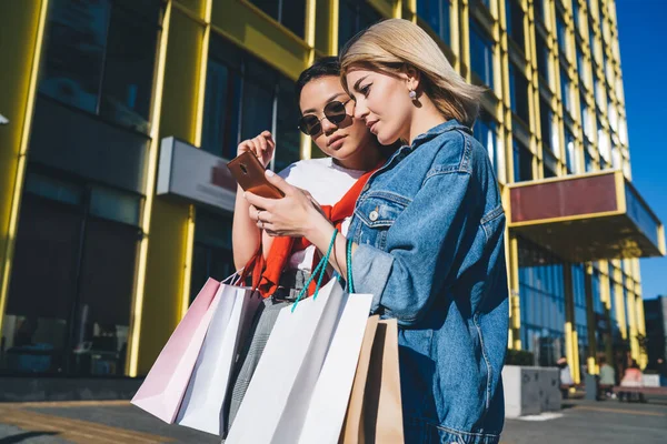 Snygg Kvinna Promenader Med Etnisk Kvinna Solglasögon Med Shoppingväskor Och — Stockfoto