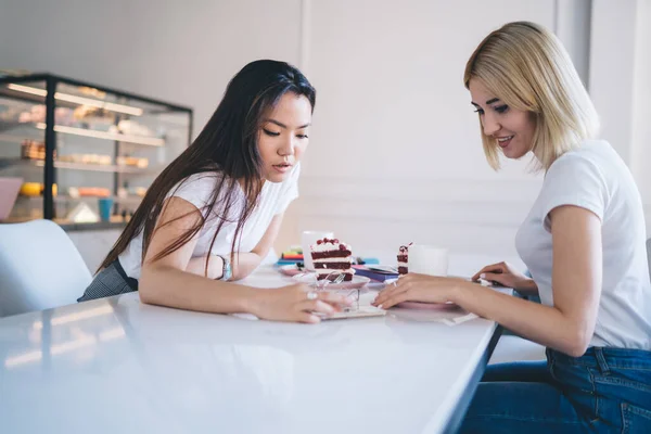 Vielrassige Frauen Weißen Shirts Sitzen Tisch Mit Kuchenstücken Aus Kaffeekapseln — Stockfoto