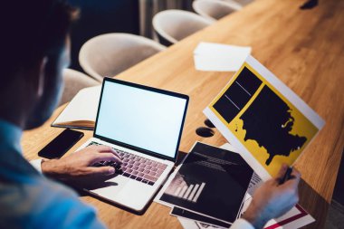 Beyaz tişörtlü, elinde haritayla çalışan isimsiz bir adamdan. Ofiste bilgisayarlı akıllı telefon belgeleriyle masada oturuyor. 