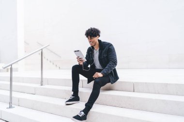 Gülümseyen erkek blogcu kulaklıkla komik film seyrediyor, hipster adam dijital tablet üzerinden olumlu arkadaşça video konuşması yapmak için şehir ortamında zaman harcıyor.