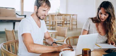 Gündelik kıyafetlerle gezen mutlu genç işçiler kafede oturuyor dizüstü bilgisayarlarında yazı yazıyor ve proje üzerine fikirler yazıyorlar.