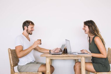 Sevgili çift laptopta haber okurken gülüyor ve tartışıyorlar. Birbirlerine bakıyorlar ve hafta sonu sabahının tadını çıkarıyorlar.