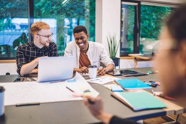 Dişli iş arkadaşları sosyal platformdan eğlenceli videolar tartışıyor modern dizüstü bilgisayarda pozitif şebeke kurmak için ara veriyorlar, mutlu arkadaşlar gülüyor ve Netbook 'ta gezinmek için 4G kablosuz internet kullanıyorlar.
