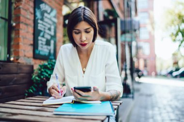 Çekici kadın blogcu, sokak kafeteryasında öğrenme sırasında interneti taramak için 4G kablosuz internete bağlı hücresel bir e-posta aldı.