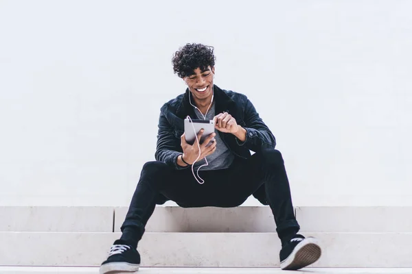 Uśmiechnięty Afroamerykanin Młody Mężczyzna Siedzący Schodach Piszący Tablecie Słuchający Muzyki — Zdjęcie stockowe