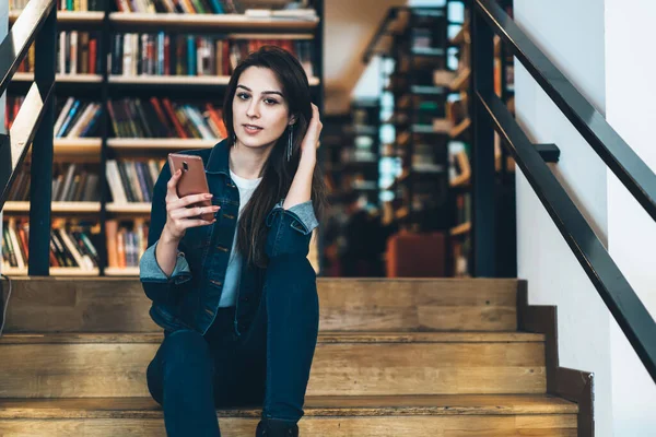 Aşağıdan Üniversitenin Kütüphanesinde Merdivenlerde Otururken Kameraya Bakıp Cep Telefonu Kullanan — Stok fotoğraf