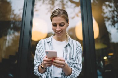 Saatli ve kırmızı manikürlü neşeli genç bayandan, akıllı telefon kullanarak pencerenin önündeki mesaja kadar.