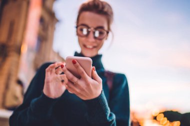 Çevrimiçi iletişim için 4G kablosuz internet bağlantısı olan modern cep telefonu cihazına seçici odaklanma, cep telefonuyla göndermek için bulanık arkaplan mesajı yazan bin yıllık kadın