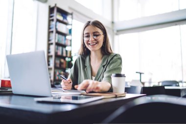 Kütüphanede araştırma yapan gözlüklü, sıradan bir esmer. 