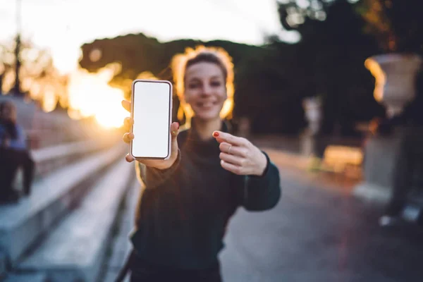 Selective focus on smartphone display with copy space area for text delivery advertising, millennial woman on blurred background holding cellular phone with blank screen for your media website