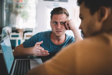 Gündelik giysilerle kaşlarını çatan serbest çalışan, ortakla birlikte kafede el ele oturarak kooperatif proje tartışması stratejisi oluşturan,