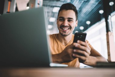 İş yerindeki masada oturan, arkadaşlarıyla cep telefonu sohbeti yapan, günlük kıyafetli, pozitif bir adamdan.
