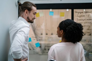 Beyaz gömlekli, belinde ciddi bir adam. Ofisteki cam panoda bilgi veren dikkatli bir bayanla işe başlıyor.