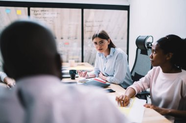 Ciddi genç iş kadını, yönetim kurulunda toplanırken, çeşitli meslekdaşlarına girişim projesi ve kurumsal anlaşma hakkında ısrarla fikir beyan ediyor.
