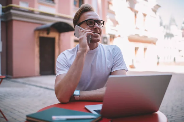 Elégedett Felnőtt Férfi Szemüvegben Néz Félre Beszél Mobilon Miközben Dolgozik — Stock Fotó