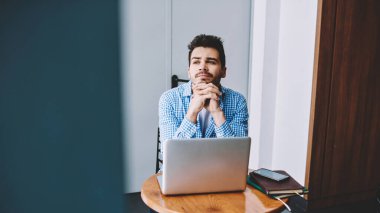 Düşünceli, odaklanmış, elleri sımsıkı bağlı bir adamdan dizüstü bilgisayarını kullanarak iş yerinde oturduğu yerden gözlerini kaçıran bir proje yaratıyor.