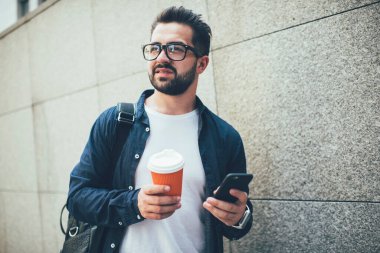 Gündelik kıyafet ve gözlüklü yakışıklı beyaz adam sokakta cep telefonu kullanıyor. Düşünceli erkek öğrenci cep telefonuyla mektup yolluyor. Şehir merkezine gitmek için kahveyle geziyor.
