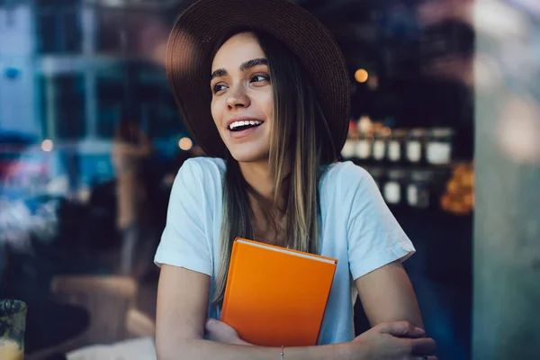 Delighted Joyful Young Lady Hugging Orange Book Smiling While Sitting — Stock Photo, Image