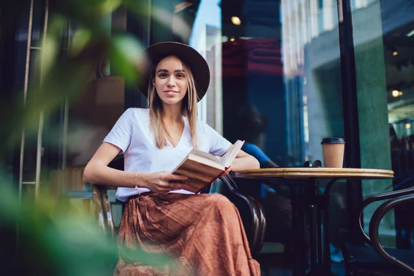 Cheerful Woman Trendy Clothes Hat Reading Book While Sitting Table — Stock Photo, Image