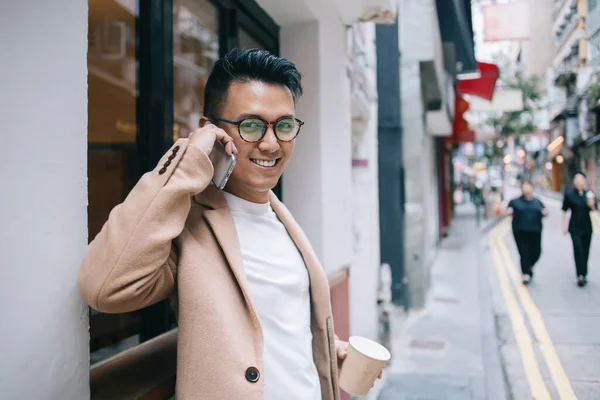 Content Asian Male Entrepreneur Trendy Beige Coat Speaking Mobile Phone — Stock Photo, Image