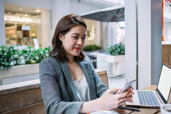 Unga Asiatiska Kvinnliga Frilansare Meddelande Smartphone Medan Sitter Café Träbord — Stockfoto