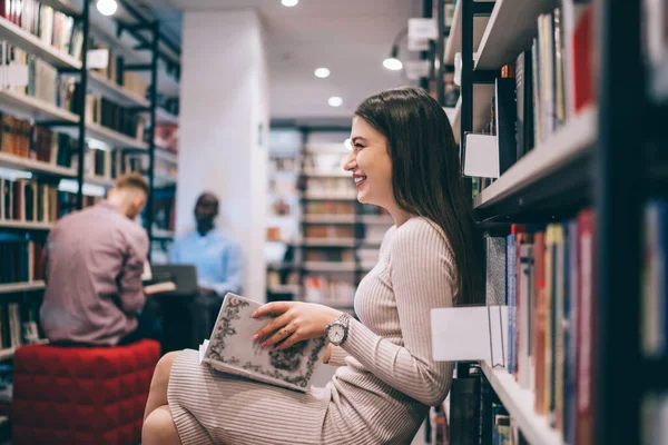 Zijaanzicht Van Vrolijke Vrolijke Vrouw Met Boek Zittend Bibliotheek Leunend — Stockfoto