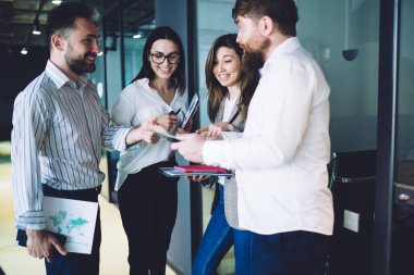 Çeşitli ofis çalışanları önemli belgeler taşıyor ve modern ofis koridorlarında işle ilgili konuları tartışıyorlar.