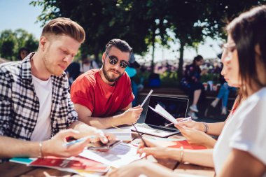 Serbest çalışanlardan oluşan bir grup yazın açık terasta dizüstü bilgisayarla konuşuyor ve oturuyorlar. 