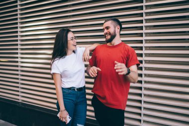 Neşeli iş arkadaşlarının birbirine bakıp gülerken açık modern ofisin bulanık beyaz çizgili duvarına karşı eğlenceli sohbetler etmesi.