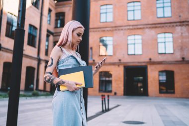 Not defterleri sütunlara dayanan ve akıllı telefondan sosyal medyayı karıştıran yoğun trend bayanın yan görüntüsü.