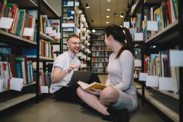 기쁘고 도서관 바닥에 여자와 이야기하면서 노트북을 사용하고 있습니다 — 스톡 사진