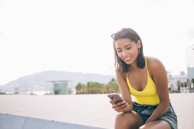 Latin çağında sosyal ağ ağlarında dijital akıllı telefondan 4g 'ye bağlı video bloğu izlemek, taşınabilirlik bilgisinin paylaşımı için mutlu hipster Y neslinin cep telefonuna mesaj yazması