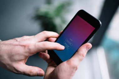 Şifreli hesap adı ve şifreyi bulanık arkaplan üzerindeki mobil uygulamaya girmek için siyah akıllı telefon kullanan tanınmayan adamın elleri