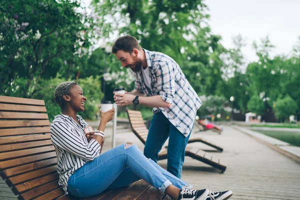 夏の都市公園での時間を過ごしながら コーヒーを飲みながら冗談を言っている多人種の幸せなカップルの側のビュー — ストック写真