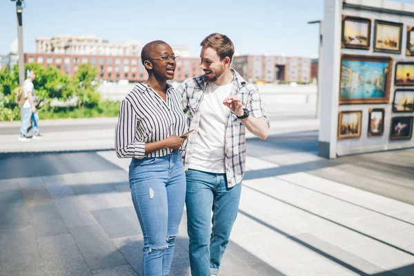 楽しい会話を楽しみながら 都会の通りを一緒に楽しみながら歩くカジュアルな服の陽気な若い多人種の友人 — ストック写真
