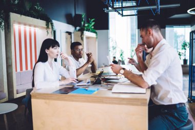 Toplantı sırasında masanın etrafında otururken ve başlangıç projesi üzerinde çalışırken verileri tartışan çok ırklı ciddi meslektaşların yan görünümü