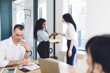 Neşe dolu, çok ırklı iş kadınlarının brifingden önce çalışma grubuyla çağdaş konferans odasında tokalaşarak selamlaşmalarının yan görünüşü
