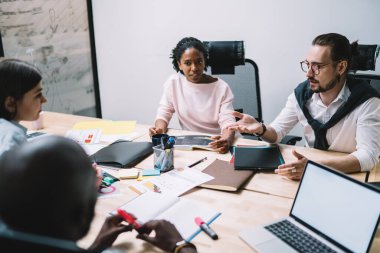 Resmi olarak dalgın girişimcinin yüksek açısı, açık modern ofis toplantılarında kağıt ve dizüstü bilgisayarla ahşap masada otururken dalgın meslektaşlarına bakış açısını açıklıyor.