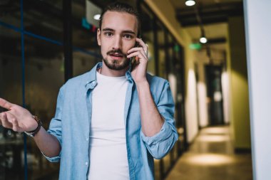 Hayal kırıklığına uğramış, sıradan kıyafetler içinde modern bir erkek cep telefonundan kötü haberler alıyor ve bina koridorunda dikilip kameraya bakarken ellerini açıyor.