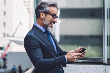 Ofisteki mutlu, olgun iş adamının yan görünüşü. New York 'ta balkonda cep telefonu ve gözlük takması.