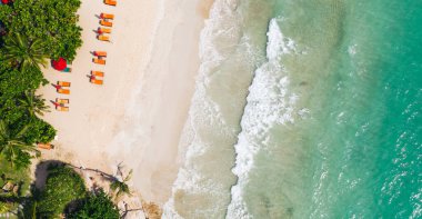 Güneş pansiyonlu deniz manzaralı otel oteli. Kuş bakışı tropikal yaz tatili manzarası, turkuaz su kıyısı, temiz kumsal şeridinde şemsiyeler. Cennet uykusu