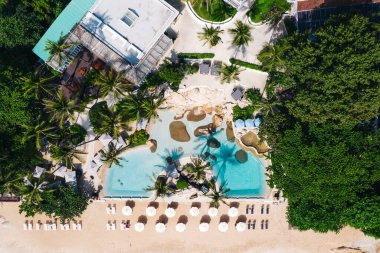 Açık yüzme havuzu ve güneş pansiyonları olan deniz manzaralı otel oteli. Yaz tatilinin kuş bakışı manzarası, temiz kumsalda şemsiyeler.